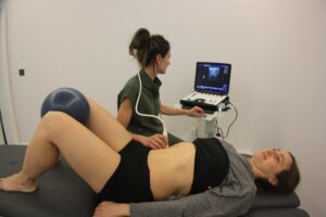 Fisioterapeuta realizando ecografía musculoesquelética a una paciente durante una sesión de fisioterapia avanzada en Getxo.