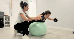 Fisioterapeuta guiando a una paciente durante una sesión de ejercicio terapéutico con fitball en moven FISIOTERAPIA, Getxo.