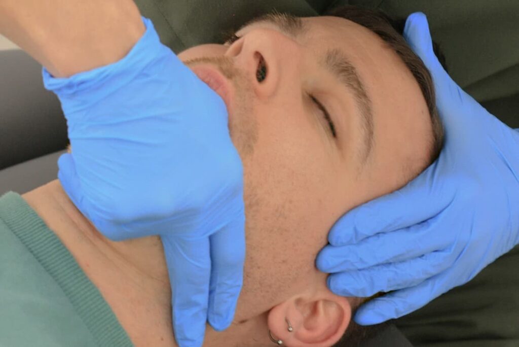 valuación manual del dolor en la mandíbula durante una exploración de la articulación temporomandibular